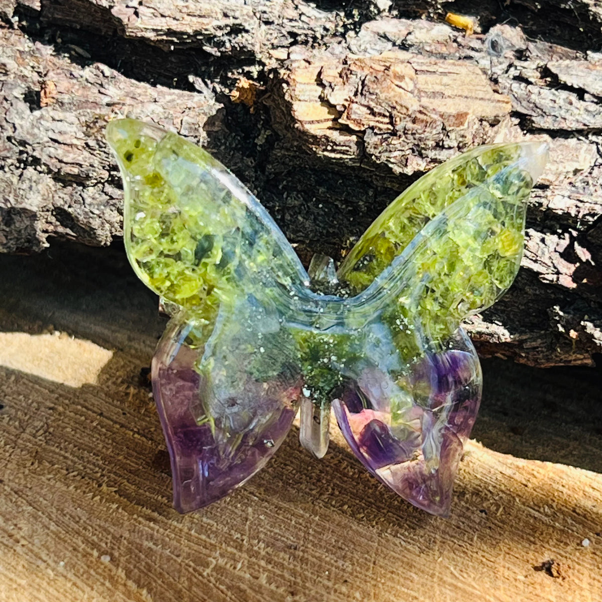 UN FLUTURE DIN PERIDOT DE CULOARE VERDE DESCHIS CU INSERCTIIE MOV PE UN SUPORT DE LEMN 